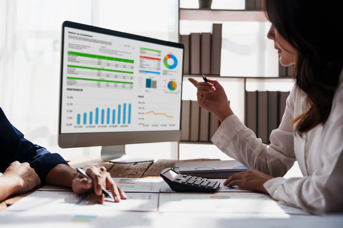 Dos personas revisan un panel de datos en la pantalla del ordenador