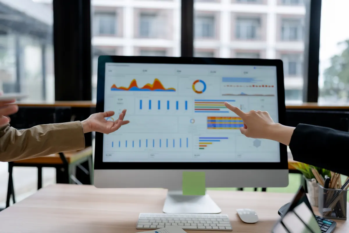 Two hands pointing at charts on a computer screen
